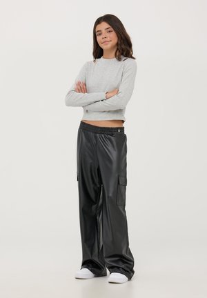 Maglietta grigia a maniche lunghe con spalle scoperte, abbinata a pantaloni cargo neri in ecopelle con tasche laterali e cintura elastica.