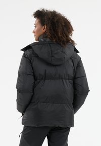 Svart puffjacka med huva, med en quiltad design och texturerad yta. Justerbar dragsko i nederkant. Försedd med en logopatch.