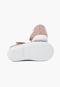 Chaussures en toile beiges avec une tige texturée, semelles en caoutchouc blanches et une bride Velcro pour la fermeture. Caractéristiques de couture soignée et d'un léger talon.