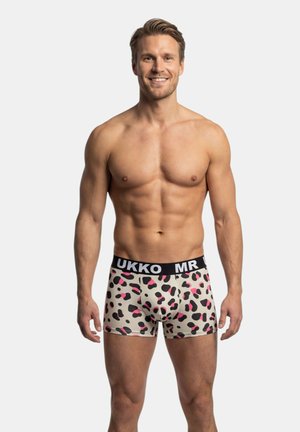 Bokserki w beżowym kolorze z abstrakcyjnymi czarnymi i różowymi plamami, z czarnym paskiem w talii z białym napisem. Elastyczny materiał i dopasowany krój.