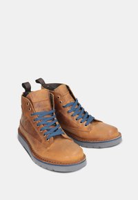 Stivaletti in pelle marrone con lacci blu, punta rotonda, suola in gomma grigia e linguette sul retro per una facile calzata.
