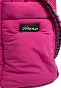 Roze gewatteerde tas met een logo patch met "CLIO GOLDBRENNER" en een multi-kleurige gevlochten schouderband. Glad textuur, zachte materiaal.