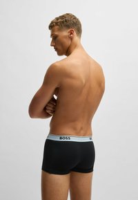 Schwarze Boxershorts mit einem kontrastierenden hellblauen Gummibund, der das Logo "BOSS" trägt. Glattes, enges Design mit mittelhohem Schnitt.