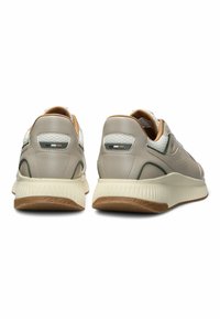 Sneaker beige con pannelli laterali testurizzati, colli imbottiti e suole in gomma. Presentano un'accaente verde scuro e un motivo esagonale sul tallone.