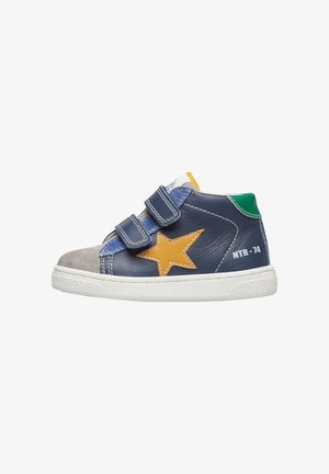 Kinder sneaker van marineblauw leer, grijze neus, gele ster, groene hieltab en twee klittenbandsluitingen op een witte zool.