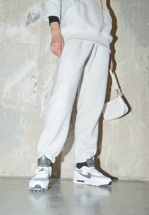 Light gray fleece hoodie with black accents, matching joggers, and white Nike sneakers with gray details. Small white crossbody bag.
