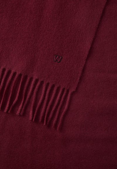 Bordeaux uldhal med frynser; har et lille broderet "W"-logo. Blød tekstur med ensartet udseende. Firkantet form.