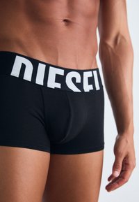 Fekete pamut boxer alsó széles fehér "DIESEL" logós derékpánttal, szoros illeszkedéssel és sima textúrával. Minimális varrások és minta nélküli.