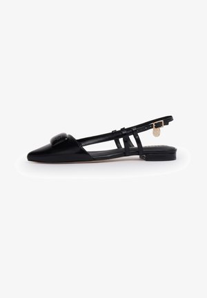 Ballerine noire à bout pointu avec bride slingback, finition vernie, doubles brides latérales, petite boucle dorée et emblème décoratif sur l'orteil.