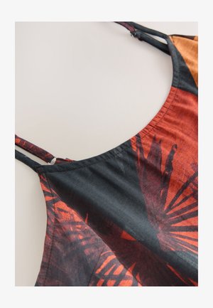 Fekete és narancssárga mintás szövet laza, áramló mintával. Vékony pántokkal és kerek nyakkivágással rendelkezik. Texturált felület élénk színekkel.