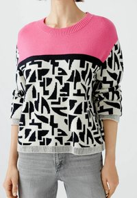 Pull tricoté comportant une section supérieure rose, un motif abstrait noir et blanc en dessous, des manches longues et des poignets et un ourlet côtelés.