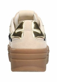 Beige sneaker with suede upper, gold metallic accent at heel, black detailing, and a thick, textured tan sole. Minimalist design.