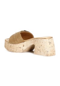 Woven tan slide sandal with a cork platform sole, featuring a rounded toe, and a gold-tone buckle accent on the strap.