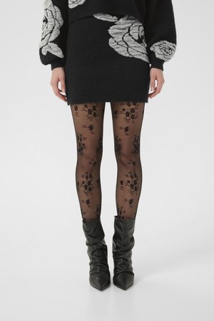 Black knit sweater with white rose patterns, a black mini skirt, floral patterned sheer tights, and black slouchy ankle boots.