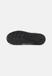 Black rubber shoe sole with a textured tread pattern, featuring grooves and ridges for traction and stability. Plain background.