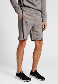 Grå atletiska shorts med en strukturerad yta, med svarta sidoliknande ränder och en broderad logotyp. Designade med fickor med dragkedja och ett elastiskt midjeband.