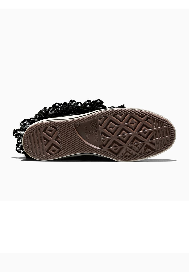 Suela de zapatilla Converse All Star negra con suela de goma marrón y detalle de volantes negros alrededor del borde.