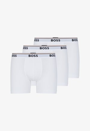 Hvide boxer shorts i en pakke med tre, lavet af blødt materiale. Har en sort-logoet elasticbånd med horisontale striber.