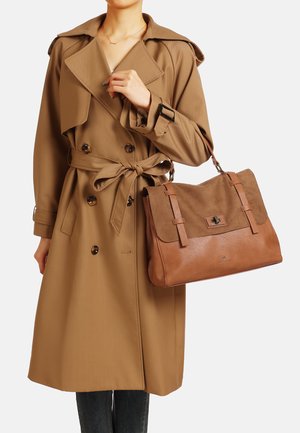 Cappotto lungo marrone con ampio colletto e cintura, abbinato a una borsa in pelle marrone con patta in suede e dettagli in metallo.