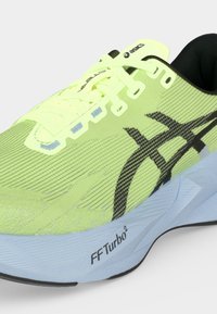 Ανοιχτό πράσινο παπούτσι τρεξίματος Asics με μαύρο λογότυπο, ανοιχτό μπλε σόλα με την ένδειξη "FF Turbo²" και κίτρινα κορδόνια.