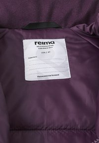 Fioletowa wodoodporna kurtka od środka z metką z tkaniny z napisem „reima”, rozmiar 104/4T oraz instrukcją, aby ją przekazać dalej. Miękka tekstura.