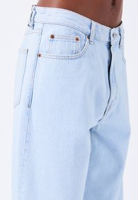 Lyseblå denim jeans med lige pasform, fem lommer og kobberdetaljer. Tekstureret stof med let pilling.