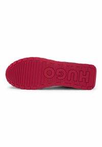 Red rubber sole with textured tread and prominent white "HUGO" branding. Flat shape designed for grip and stability.