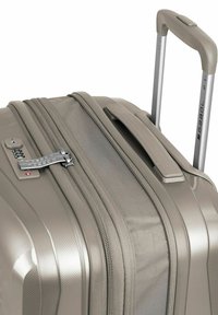Maleta rígida en taupe metálico, con superficie texturizada, doble cremallera, un asa lateral y un asa retráctil de aluminio.