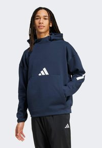 Sudadera con capucha de color azul marino, con bolsillo frontal, acento de logo blanco en el bolsillo y la manga, fabricada con material suave y de corte relajado.