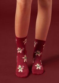 Calzini alla caviglia color marrone scuro con design di omini di pan di zenzero con accenti verdi e rossi. Il tessuto ha una texture morbida.