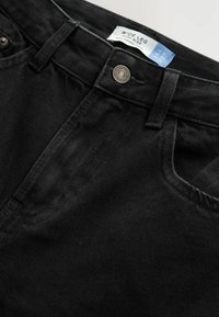 Jean noir large à taille haute avec une texture denim lisse, des poches avant et une étiquette de marque sur la ceinture.