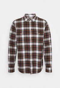 Camisa de cuadros en naranja, negro y blanco; cuello con botones; mangas largas; dos bolsillos en el pecho; material de algodón; corte regular.