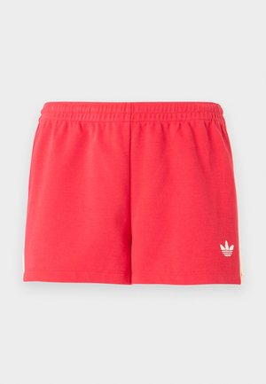 Κόκκινα αθλητικά σορτς με ελαστική μέση και μικρό λευκό λογότυπο Adidas στο κάτω αριστερό πόδι πάνω σε απλό φόντο.