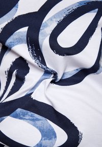 Patterned fabric featuring bold navy blue and light blue abstract shapes on a white background, displaying smooth texture and soft drape.