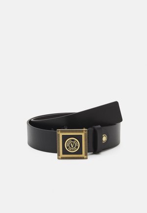 Cinturón de cuero negro con una hebilla cuadrada de oro con el logo de "Versace Jeans Couture" en el centro.