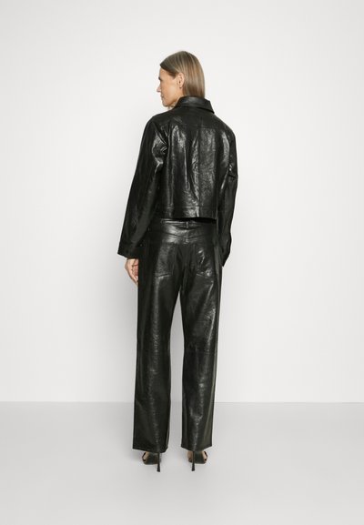 Black leather cropped jacket with a smooth texture and pointed collar, paired with high-waisted black leather pants featuring a relaxed fit.