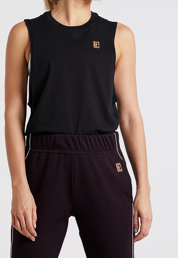 Personne portant un haut noir sans manches et un pantalon noir avec de petits logos carrés multicolores sur la poitrine et la hanche.