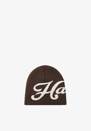 Gorro tejido marrón con grandes letras blancas en cursiva que forman parte de una palabra en el frente.