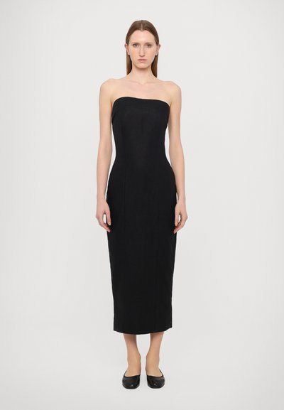 Robe noire sans bretelles avec un corsage ajusté et une silhouette droite, fabriquée en tissu lisse et arrivant mi-mollet. Conception simple, accents minimaux.
