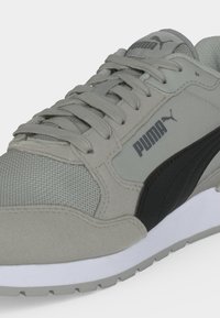 Baskets Puma gris et noir avec embout en mesh, laçage à l'avant et logos Puma visibles sur la languette et le côté.