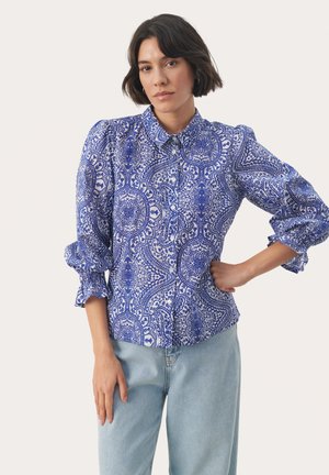 Blaue Bluse mit Muster, Kragen, Knopfleiste und Puffärmeln. Der Stoff zeigt aufwendige Paisleymuster in dunklerem Blau.