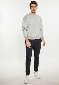 Szürke pulóver kerek nyakkal és bordás mandzsettával, fekete, slim-fit nadrággal és fehér sportcipővel párosítva. Egyszerű dizájn, nincsenek feltűnő minták.