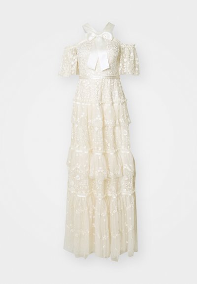 White tiered dress made of lace with embroidered floral patterns. Features short sleeves, a bow at the neckline, and a flowing silhouette.
