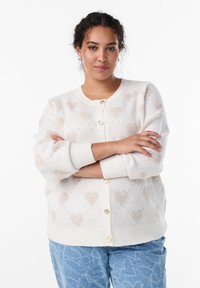 Balts adīts kardigans ar smalku sirsniņu rakstu, apaļu izgriezumu, garām piedurknēm un zelta pogām priekšpusē. Ikdienišķs piegriezums.