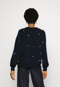 Námořnická mikina s multicolor vyšitými tečkami, dlouhými rukávy a žebrovanými manžetami. Měkká tkanina s volným střihem a kulatým výstřihem.