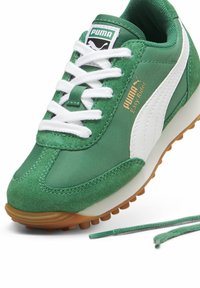 Zapatilla verde con parte superior de ante y textil, acentos blancos, suela de goma y un destacado logotipo de PUMA en la lengüeta y en el lado.