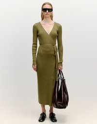 Olivgrünes, geripptes Wickelkleid mit langen Ärmeln, tiefem V-Ausschnitt und tailliertem Gurt. Kombiniert mit schwarzen Schuhen und einer burgunderfarbenen Umhängetasche.