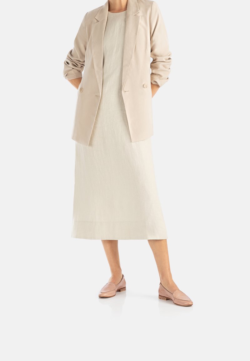 Blazer beige à manches retroussées, robe en lin crème et mocassins rose clair à texture lisse. Design simple et élégant avec des accents minimaux.