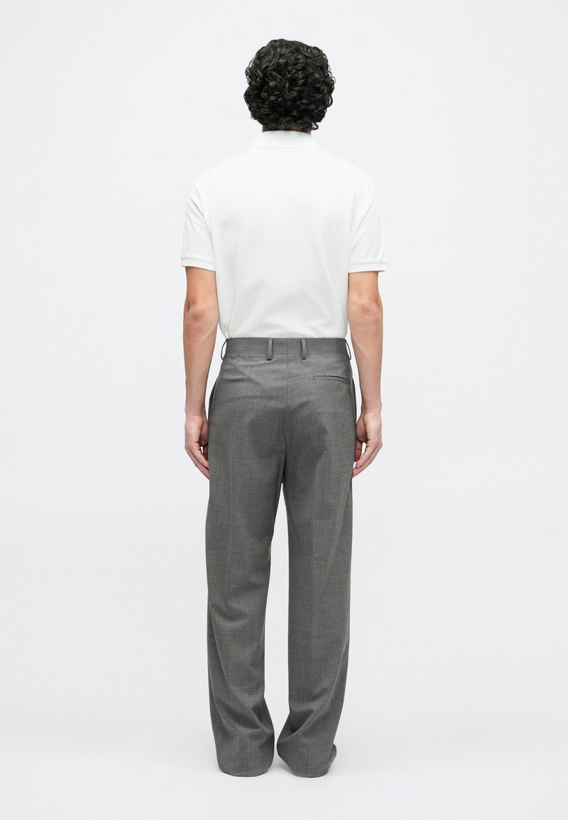 Weißes kurzärmeliges Poloshirt und graue Hose mit weitem Bein, mit glatter Textur und minimalistischem Design, von hinten betrachtet.