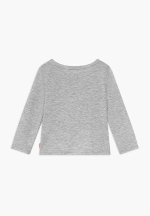 Chemise simple gris clair à manches longues avec un col rond, posée à plat sur un fond blanc, montrant le dos.